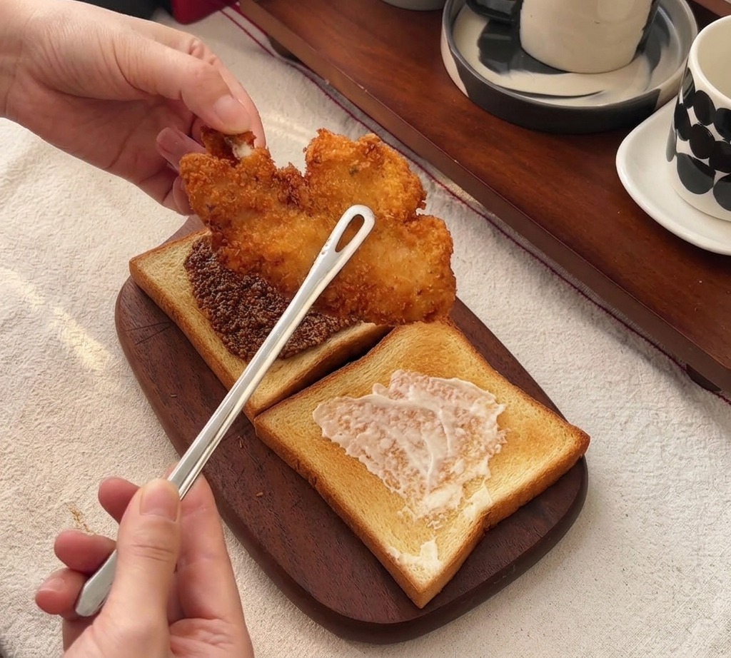 ハニーマスタードを塗ったパンの上に、大きなチキンカツをのせている様子。