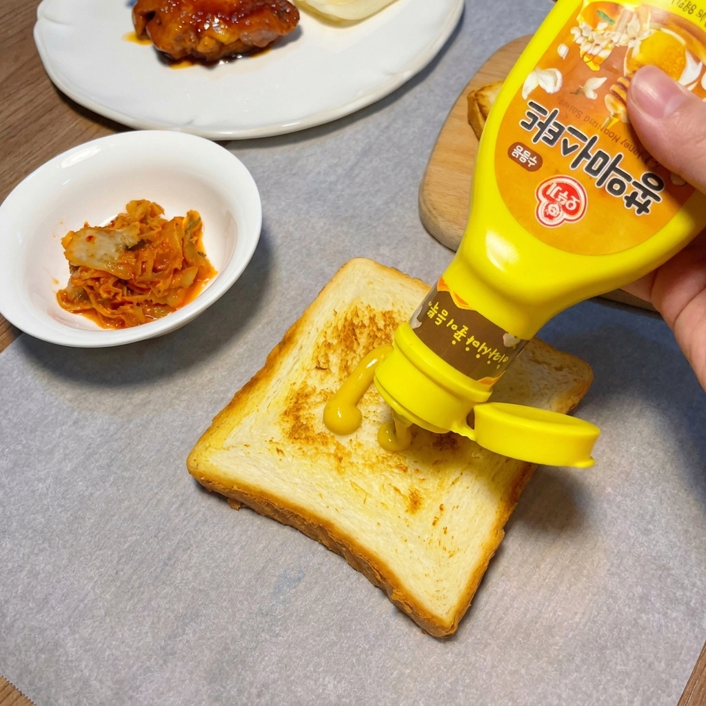 こんがりと焼けた食パンの上に、イエローマスタードがジグザグに絞られている様子。