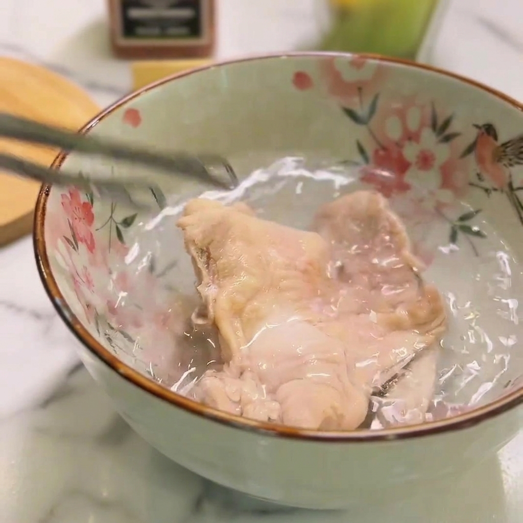 茹で上がった鶏肉を冷水の入ったボウルに移して冷ましている様子。