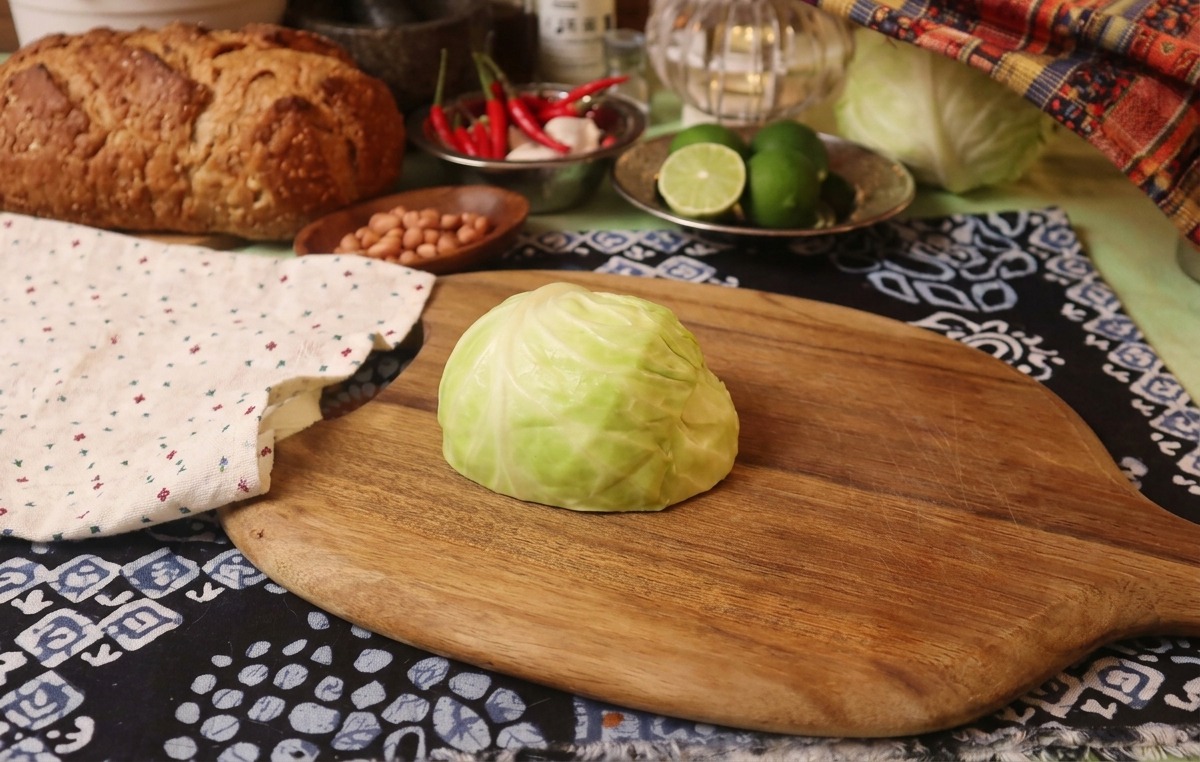 木製のまな板の上に置かれた、半分に切られた新鮮なキャベツと隣に添えられたクロス。