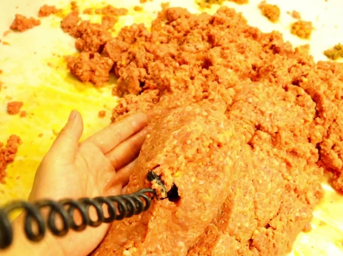 焼いたバンズの上にたっぷりとミートソースをのせる様子。