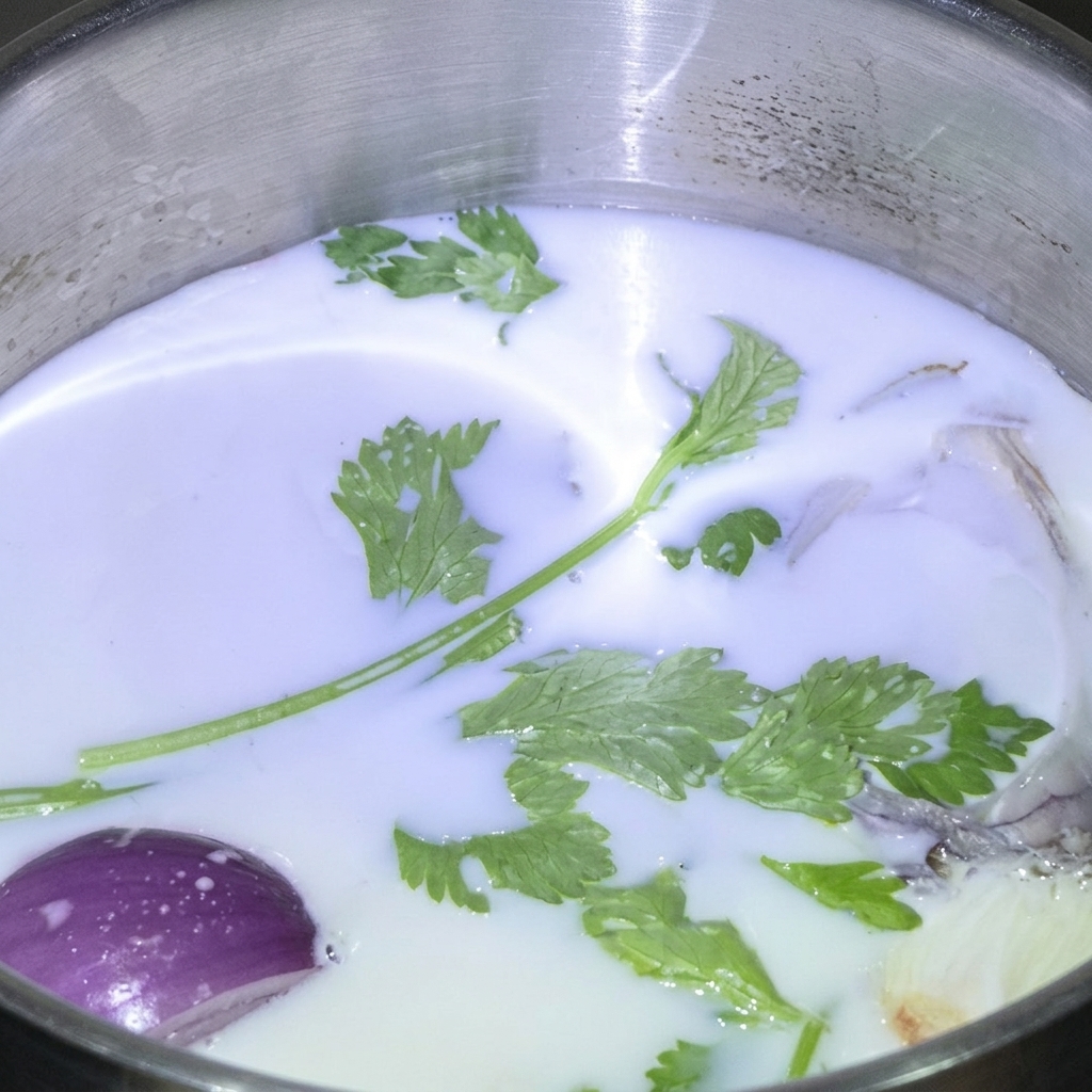 牛乳が入ったステンレス鍋に浮かぶ、フレッシュハーブと紫玉ねぎ