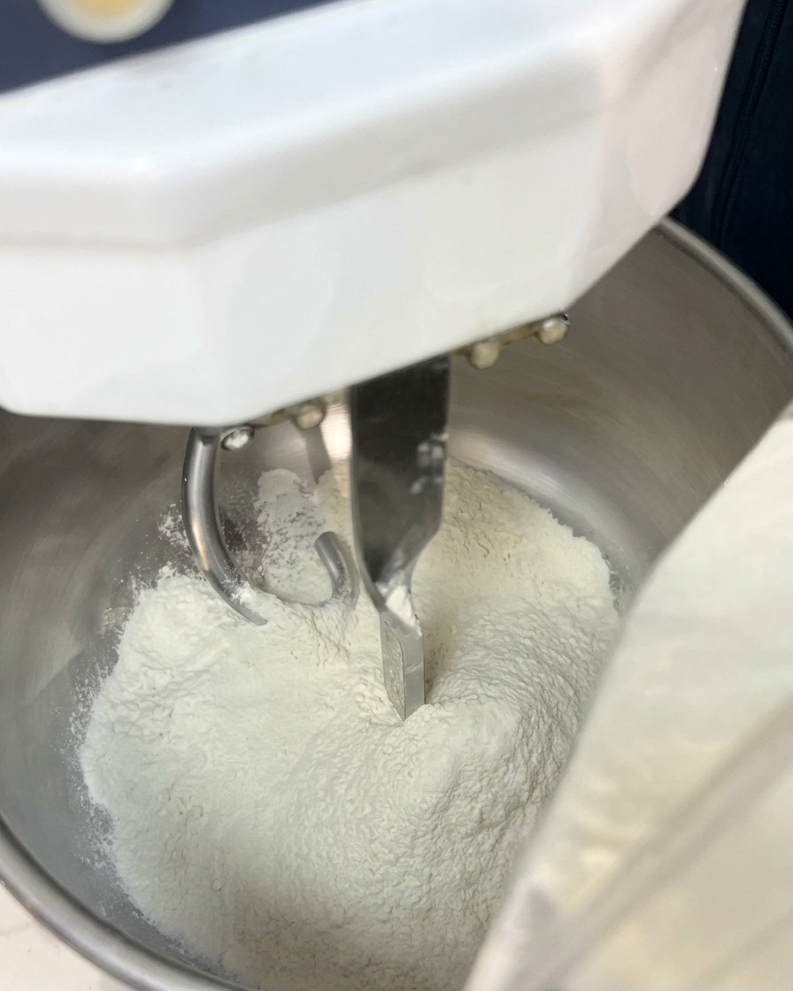 スパイラルミキサーの金属製ボウルに入った白い小麦粉。
