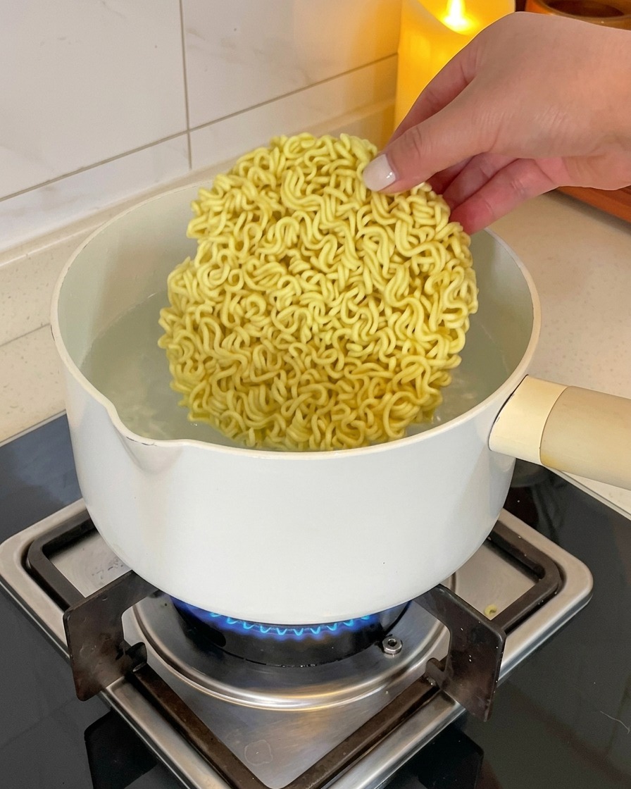 沸騰した鍋にインスタントラーメンの乾麺を入れる様子