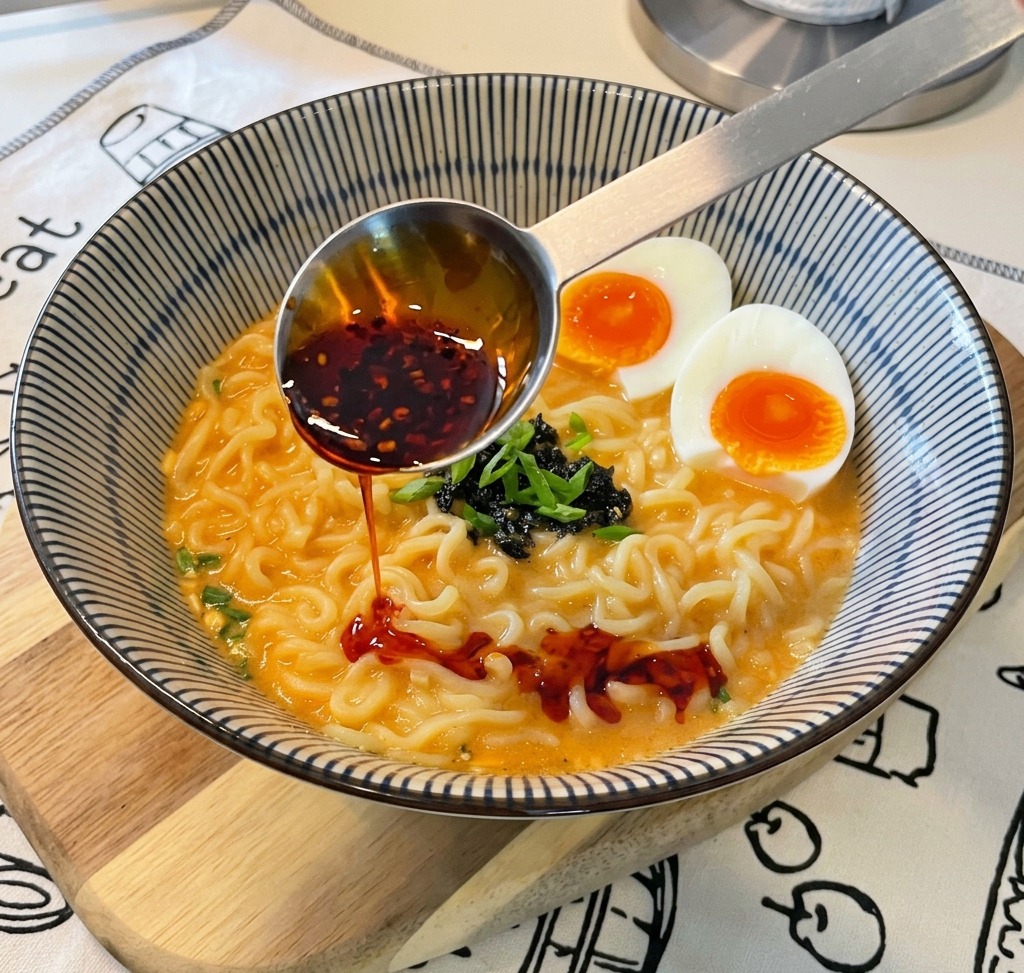 仕上げにスプーンで真っ赤なラー油をたらす様子