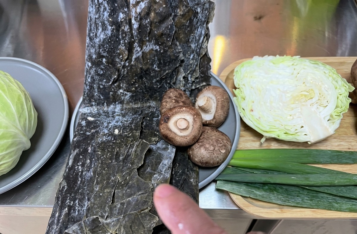 キッチンカウンターの上にきれいに並べられたキャベツ、昆布、乾燥椎茸などの新鮮な食材の数々。