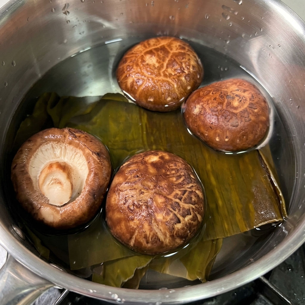 小さな鍋に張った透明な水の中に、乾燥昆布と茶色い乾燥椎茸が浸されている様子。
