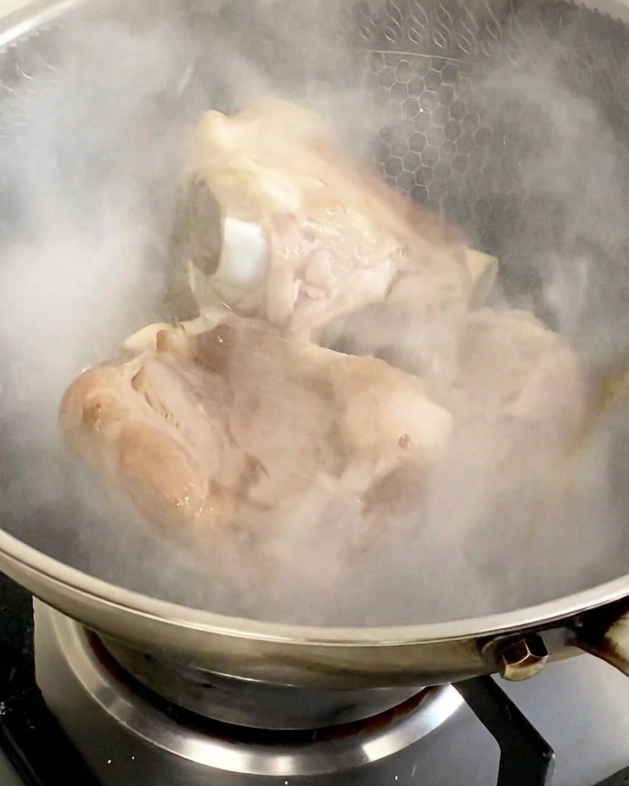 ステンレスの中華鍋に料理酒を加えた瞬間、白い湯気が一気に立ち上り、蓋を閉めようとする瞬間。