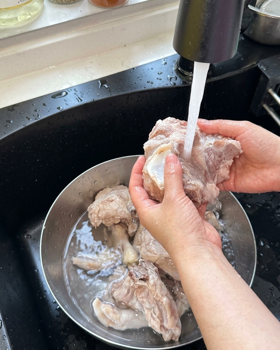 下茹でした豚骨と鶏もみじをぬるま湯で洗い流す様子。