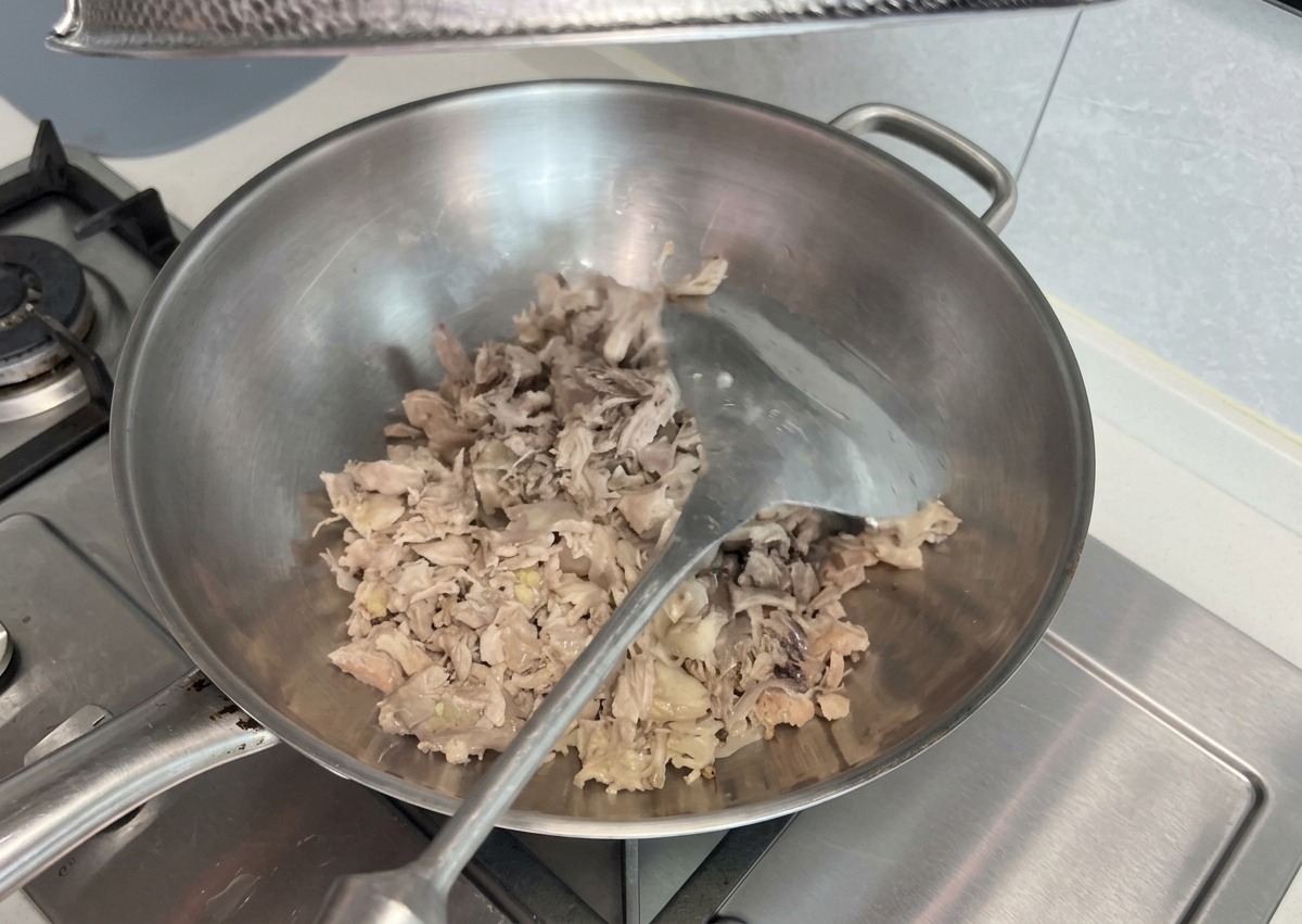 鍋の中でほぐしたお肉の端材をヘラで炒めながら潰す様子。