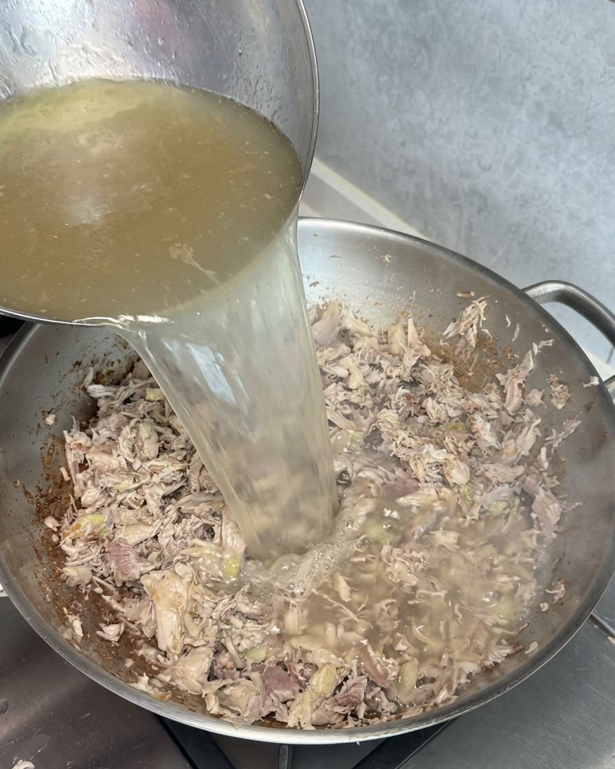 炒めたお肉の端材が入った鍋にクリアな黄金色のスープを注ぎ、白く濁る様子。