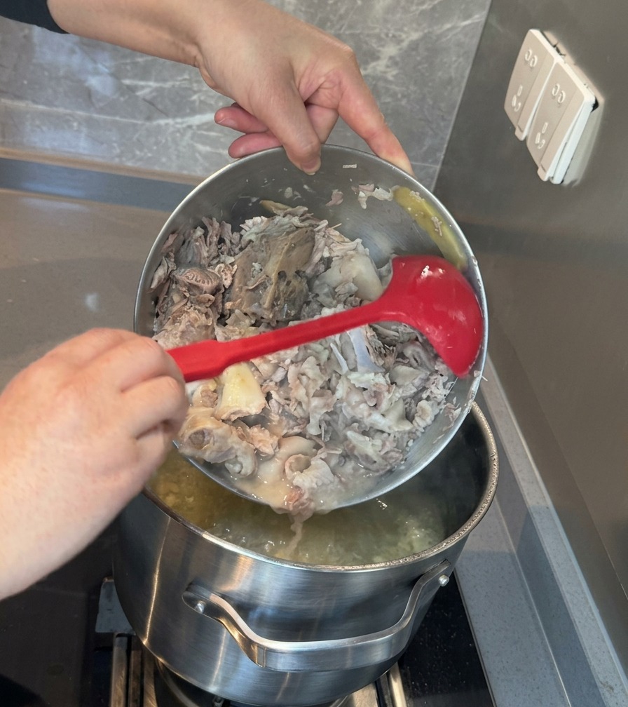 砕いた豚肉と骨髄のペーストを、白濁したスープの入った大きな鍋に戻し入れているところ。