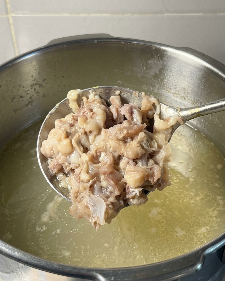 おたま一杯分の細かく潰した豚肉と鶏肉のペーストを、コトコト煮立つスープの鍋に戻そうとしている様子