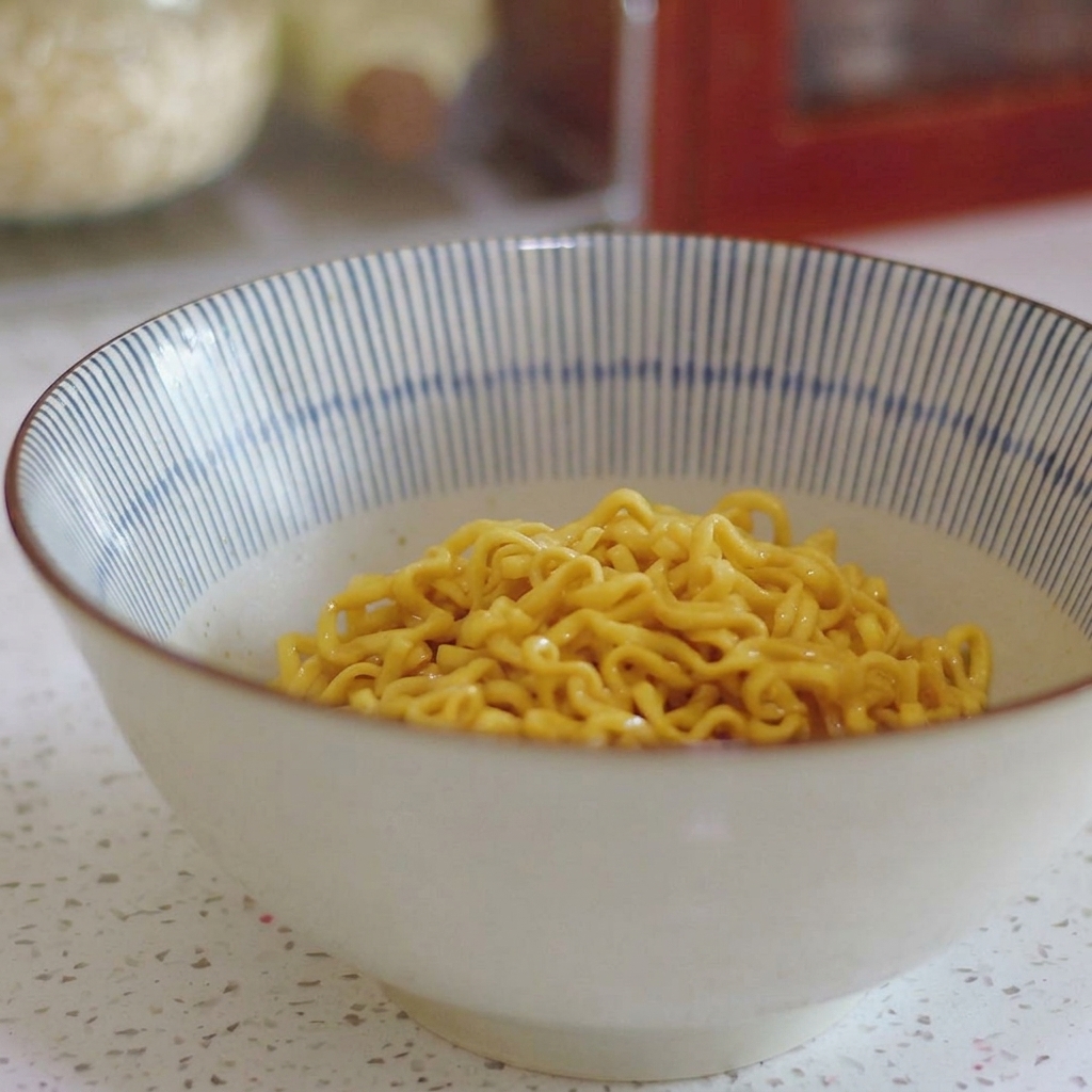青と白のストライプ模様のどんぶりの底に盛られた黄色い縮れ麺