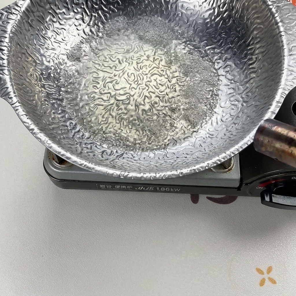 銀色の鍋の中で液体が勢いよく沸騰し、バーナーで火をつけてアルコールを飛ばしている様子。