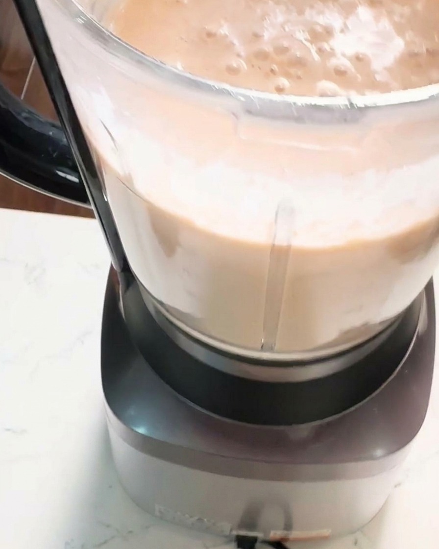 厚みがあり、滑らかでクリーミーなオレンジピンク色のエビペーストが、ブレンダーの容器の中で攪拌されている接写写真。