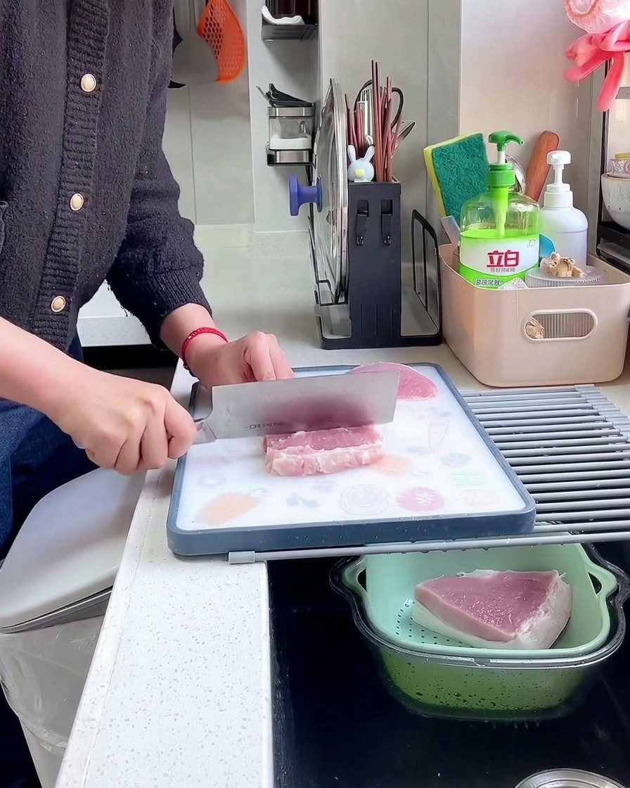 まな板の上で、肉たたき(または包丁の背)を使って生の豚肉の表面を丁寧に叩き、繊維をほぐしている手元。