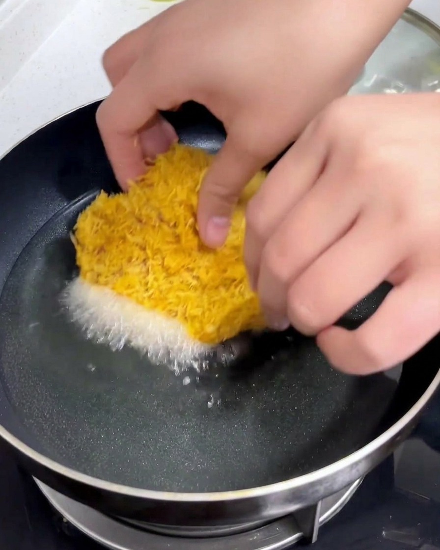 衣をつけた豚カツを、熱せられてきらきらと輝く揚げ油の入った鍋へと慎重に入れている手元。