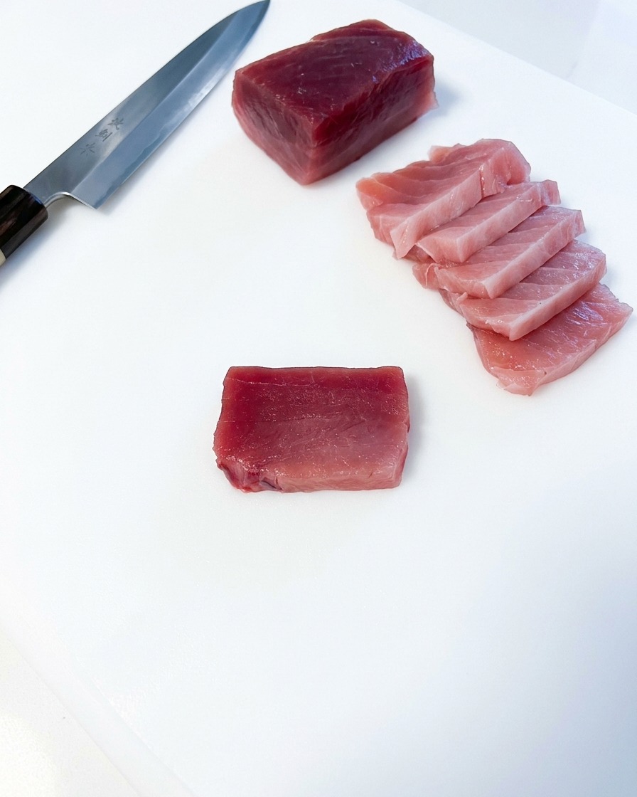 まな板の上でマグロを均等な厚さに切り分けている様子。