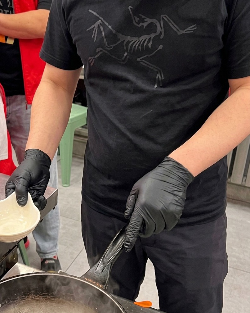 沸騰したお湯の中で、格子状に切れ目の入ったイカの身がサッと湯通しされている様子。