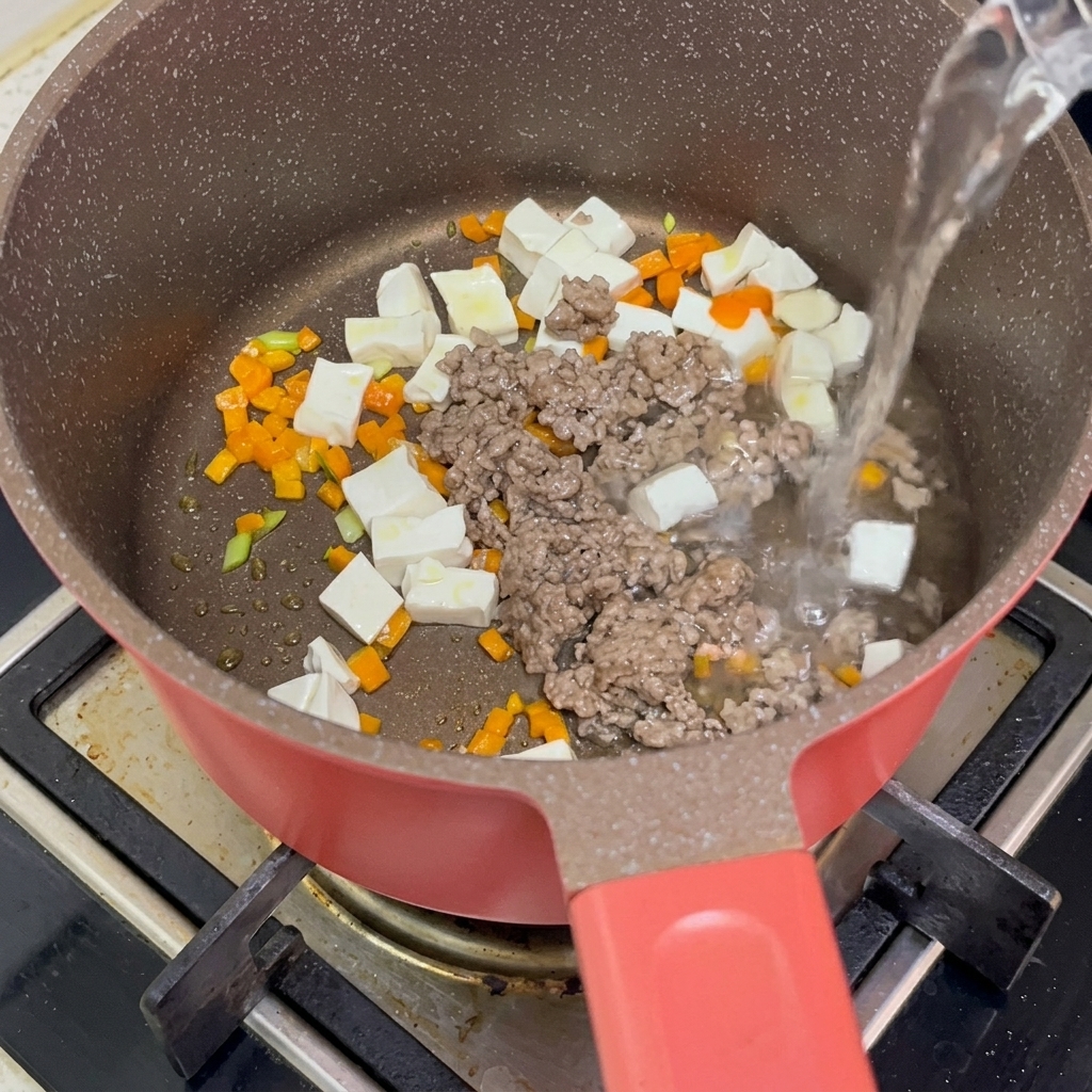 炒めた具材の中に熱湯を注ぎ込んでいる様子。