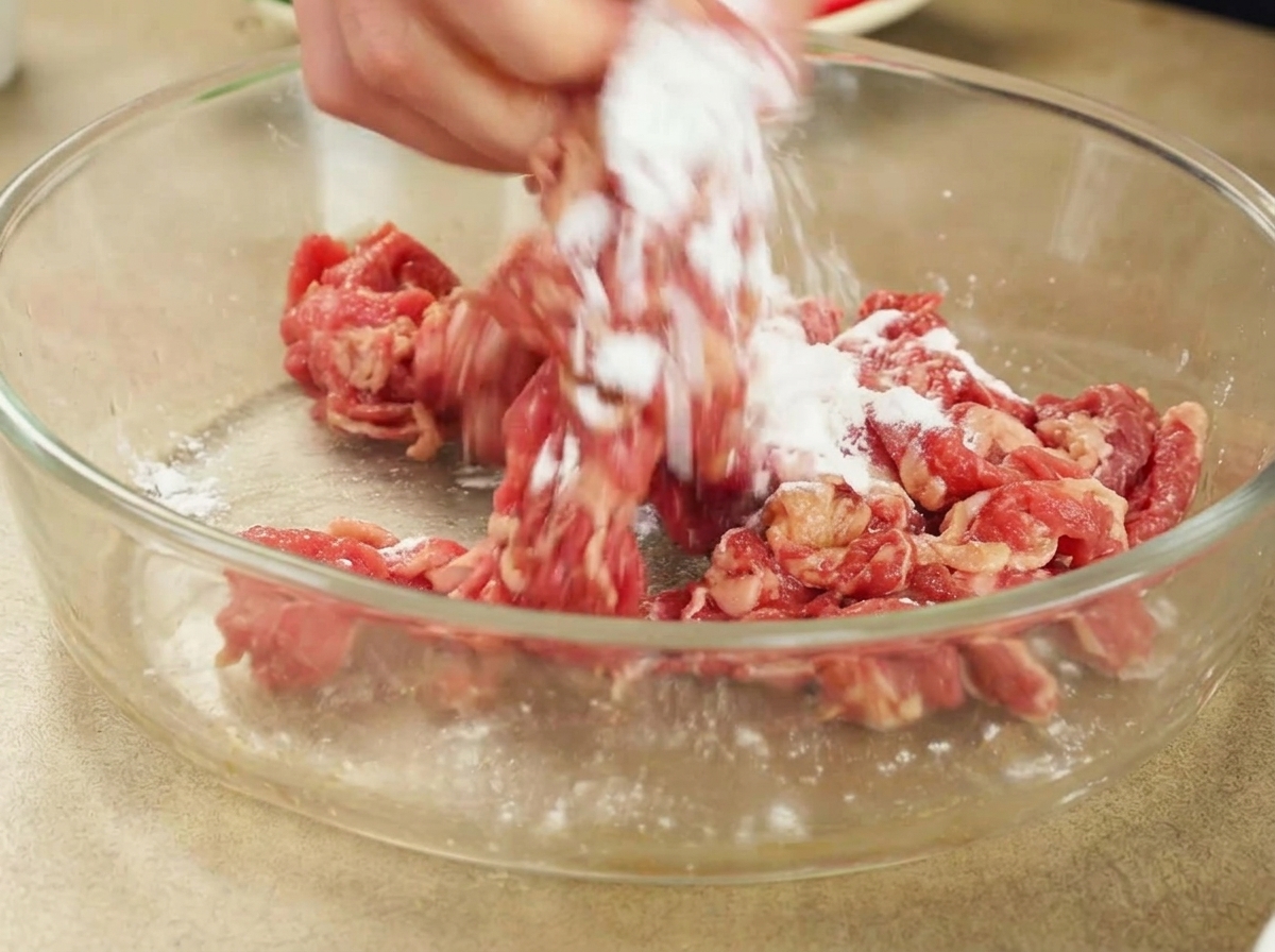手で牛肉と片栗粉を混ぜ合わせている様子。
