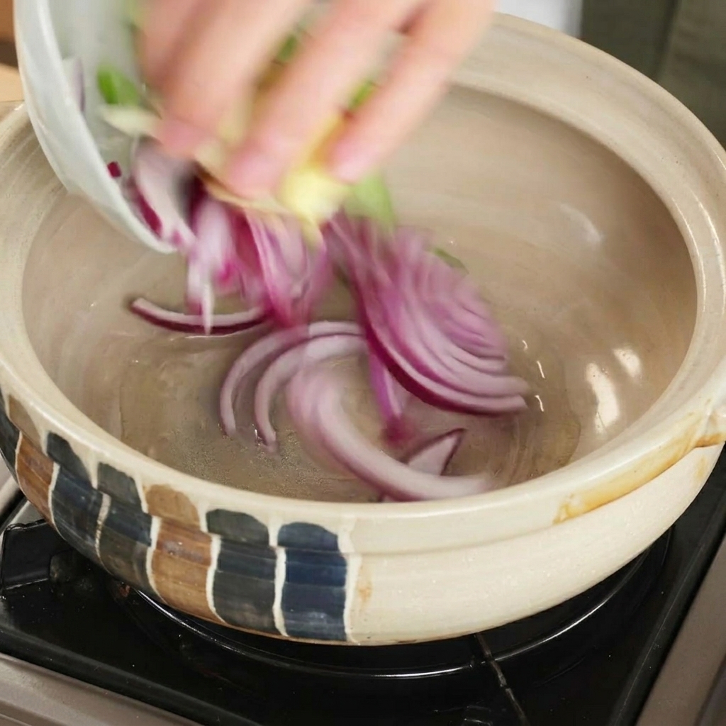 熱した土鍋に香味野菜を入れる様子。