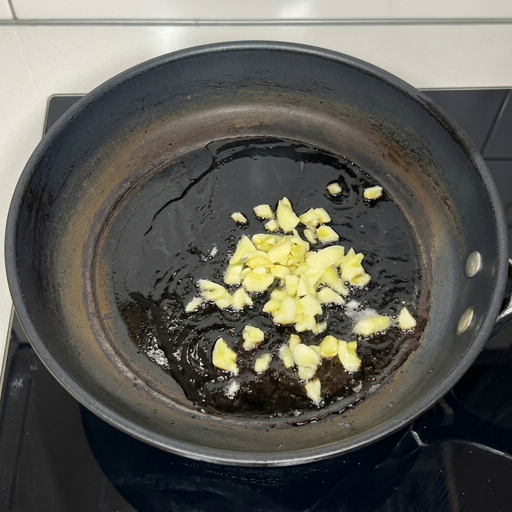 熱した油の中で、みじん切りにしたにんにくが黄金色に炒められている様子。