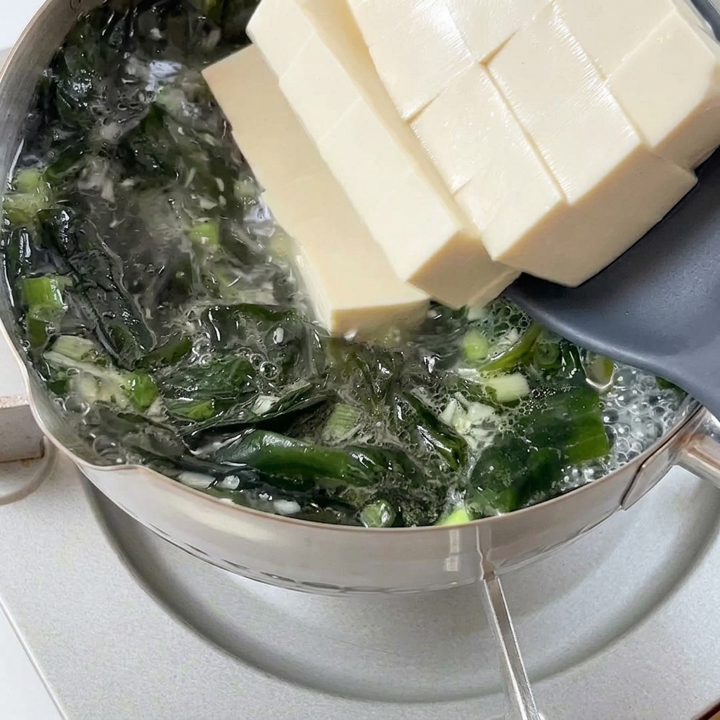 スプーンで豆腐を鍋に静かに入れている様子