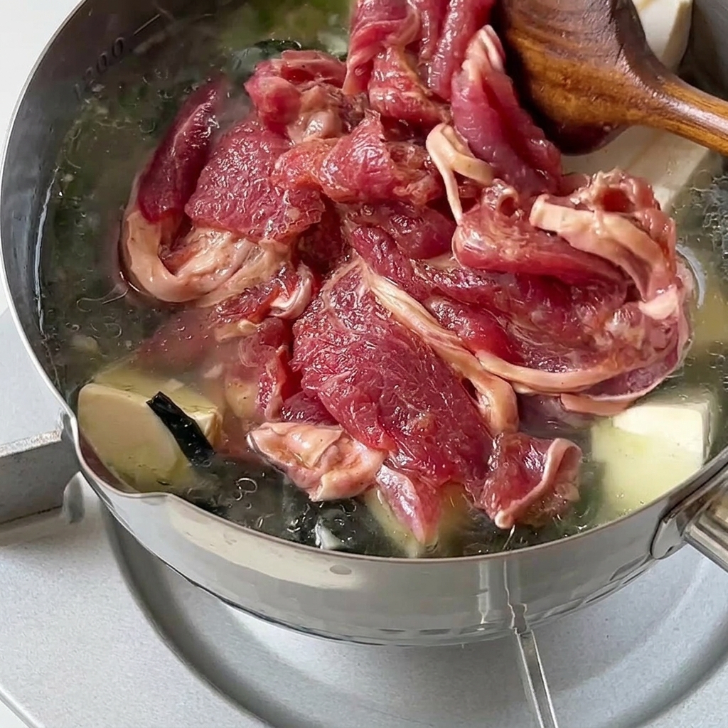 牛肉を鍋に入れて火を通している様子