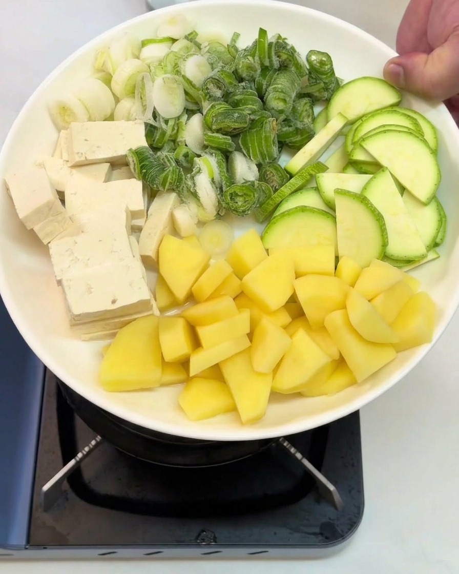角切りの豆腐、刻んだ長ねぎ、スライスしたズッキーニ、角切りの生のじゃがいもが綺麗に並べられた白いお皿。