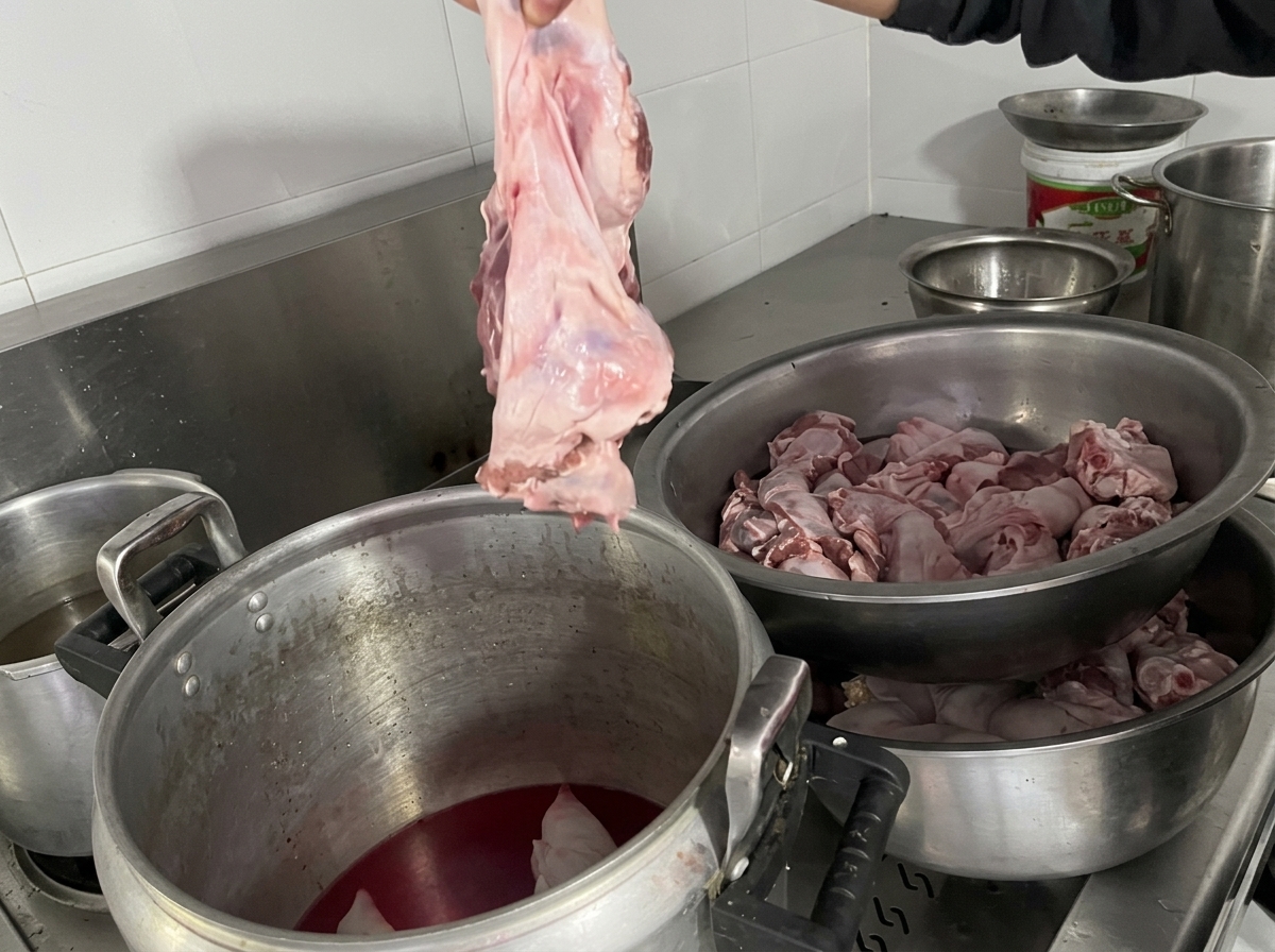 豚足と煮汁が入った鍋に、大きな牛ハラミの塊肉を入れようとしている様子