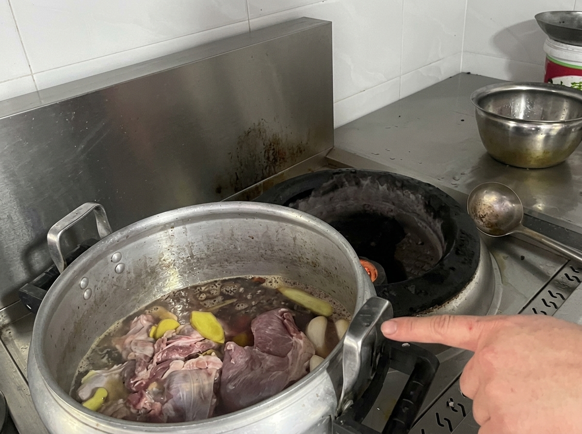 コンロの上で、肉と香味野菜が煮汁に入った大きな寸胴鍋が置かれている様子