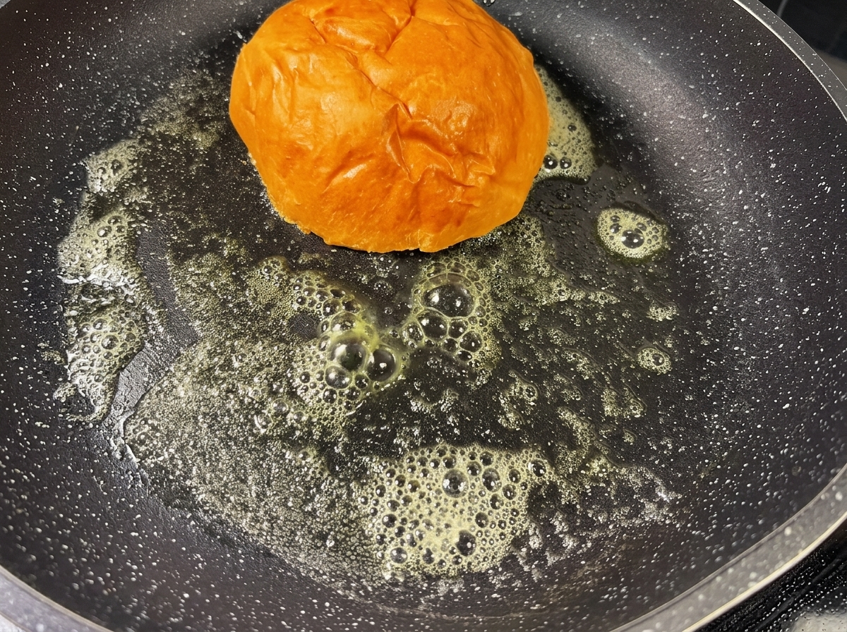 溶けたバターが広がる熱いフライパンで、きつね色にトーストされているバーガーバンズ。