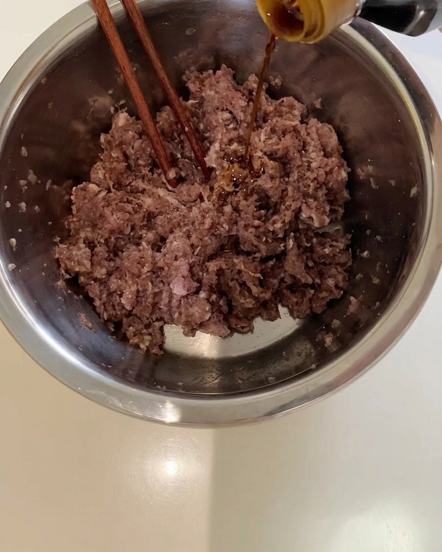 牛ひき肉が入ったボウルに醤油を注いでいる様子