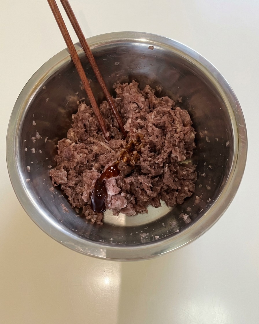 下味をつけた牛ひき肉をボウルの中で混ぜ合わせている様子