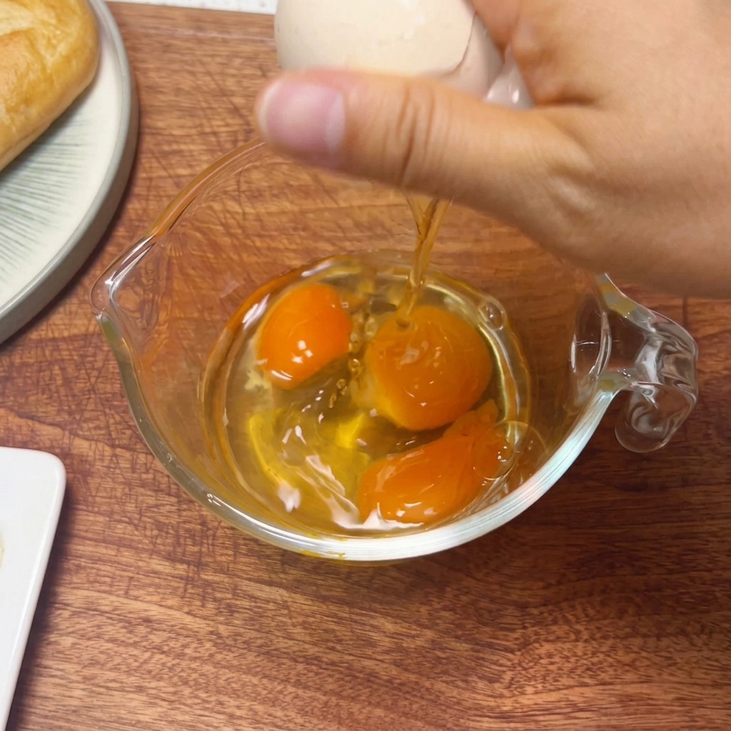 計量カップに入った3つの卵を、箸で混ぜ合わせている様子。