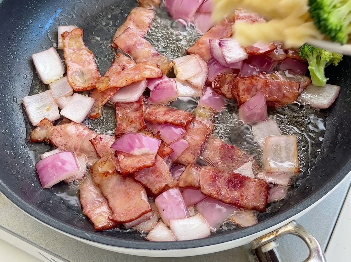 フライパンにパスタとブロッコリーを加えて和えている様子。