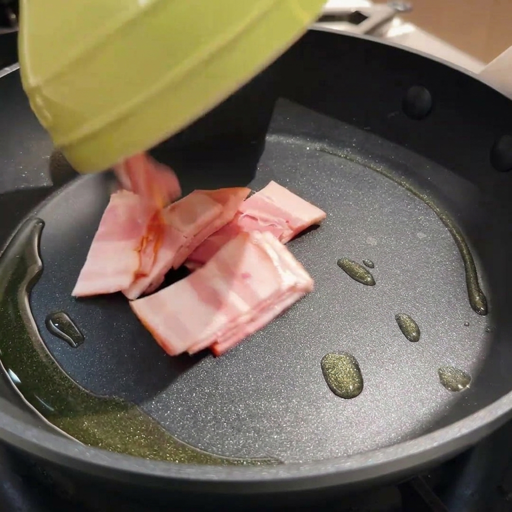 熱したフライパンでベーコンをこんがりと焼いている様子。