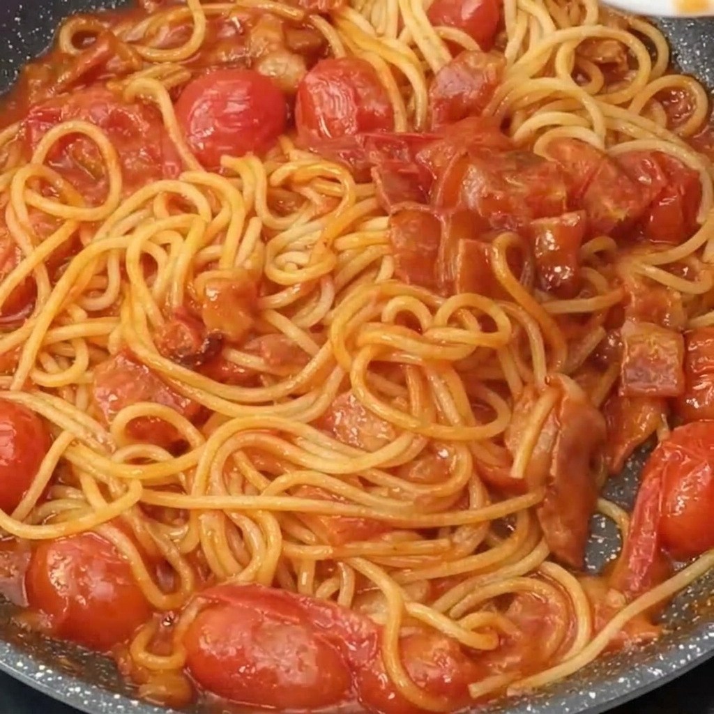 完成したパスタにパルメザンチーズが削りかけられている様子。