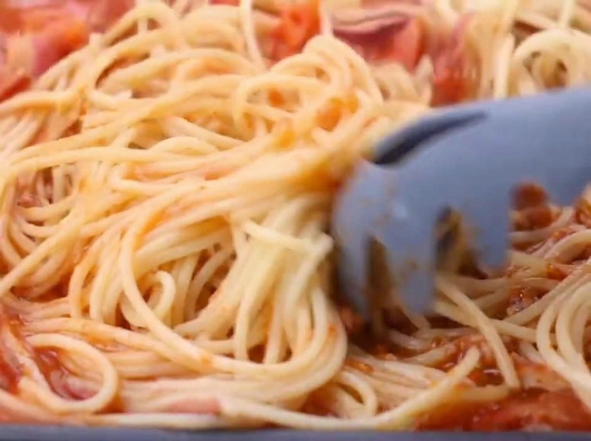茹でたての麺をソースのフライパンに加えている様子。