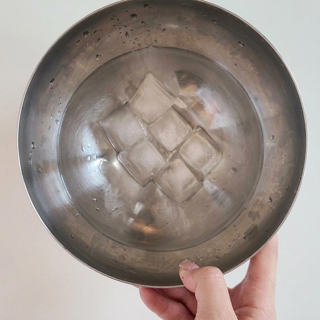 茹で上がった麺をザルに入れ、冷水で洗っている様子。