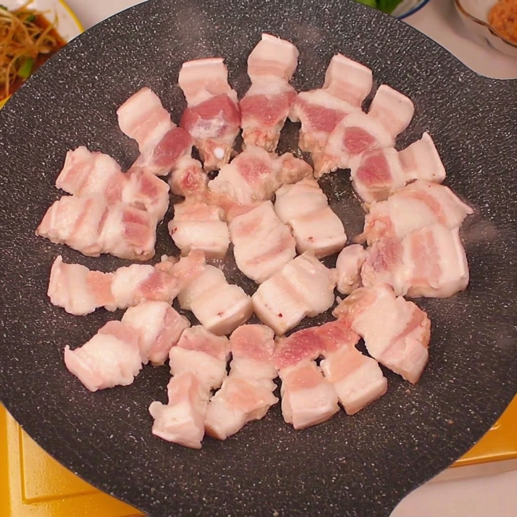 熱したグリルパンの縁に、豚バラ肉を円を描くようにきれいに並べている様子。