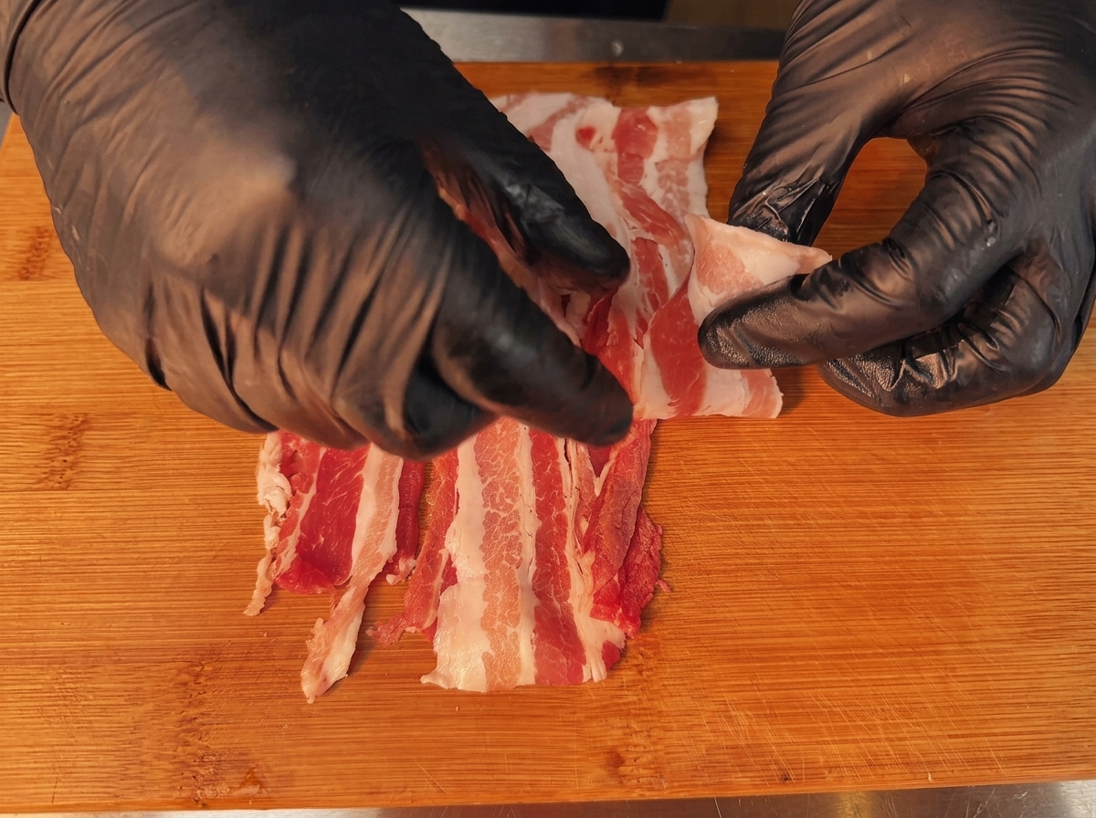 巻く準備として、少しずつ重ねて広げられた豚バラ肉。