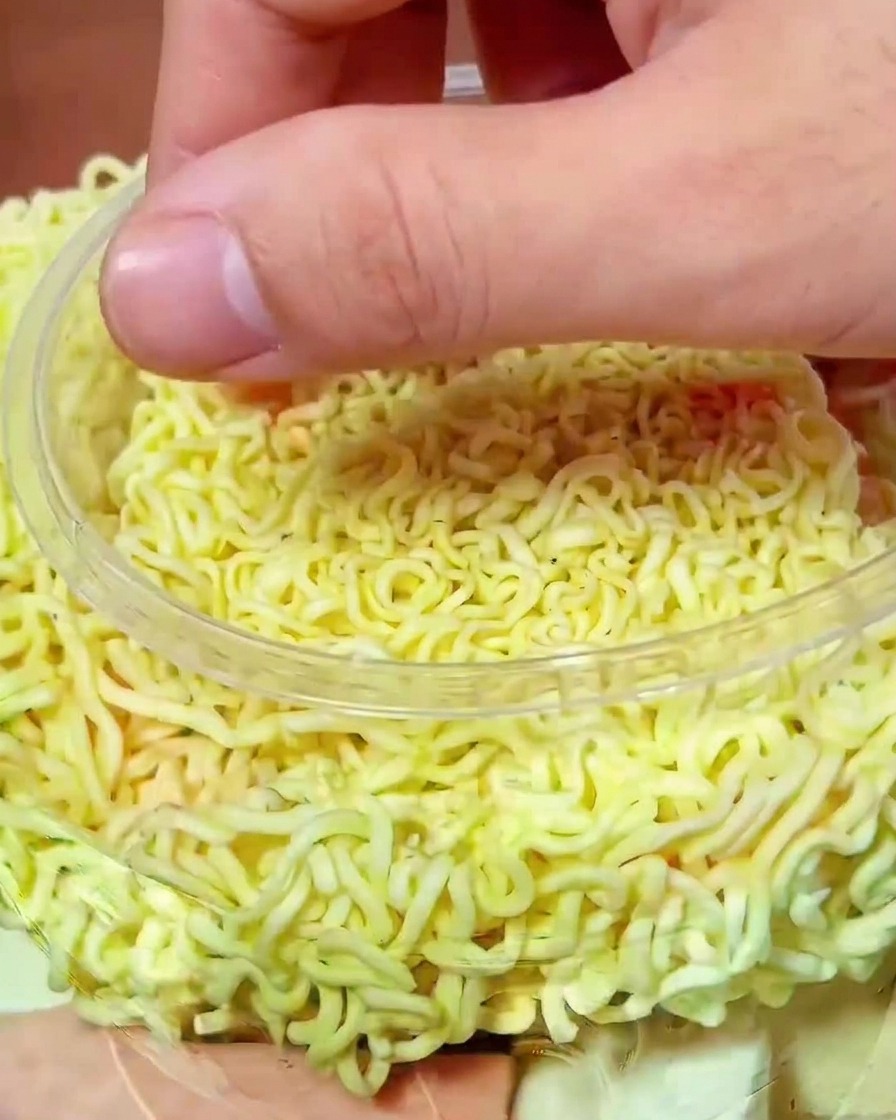 麺の上に、鮮やかな赤色のキムチがたっぷりとトッピングされている様子。
