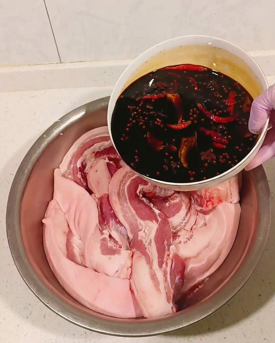 冷ましたマリネ液を豚肉に注いでいる様子