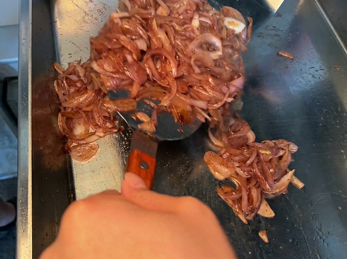 冷めたマリネ液をボウルの豚バラ肉に注いでいる様子
