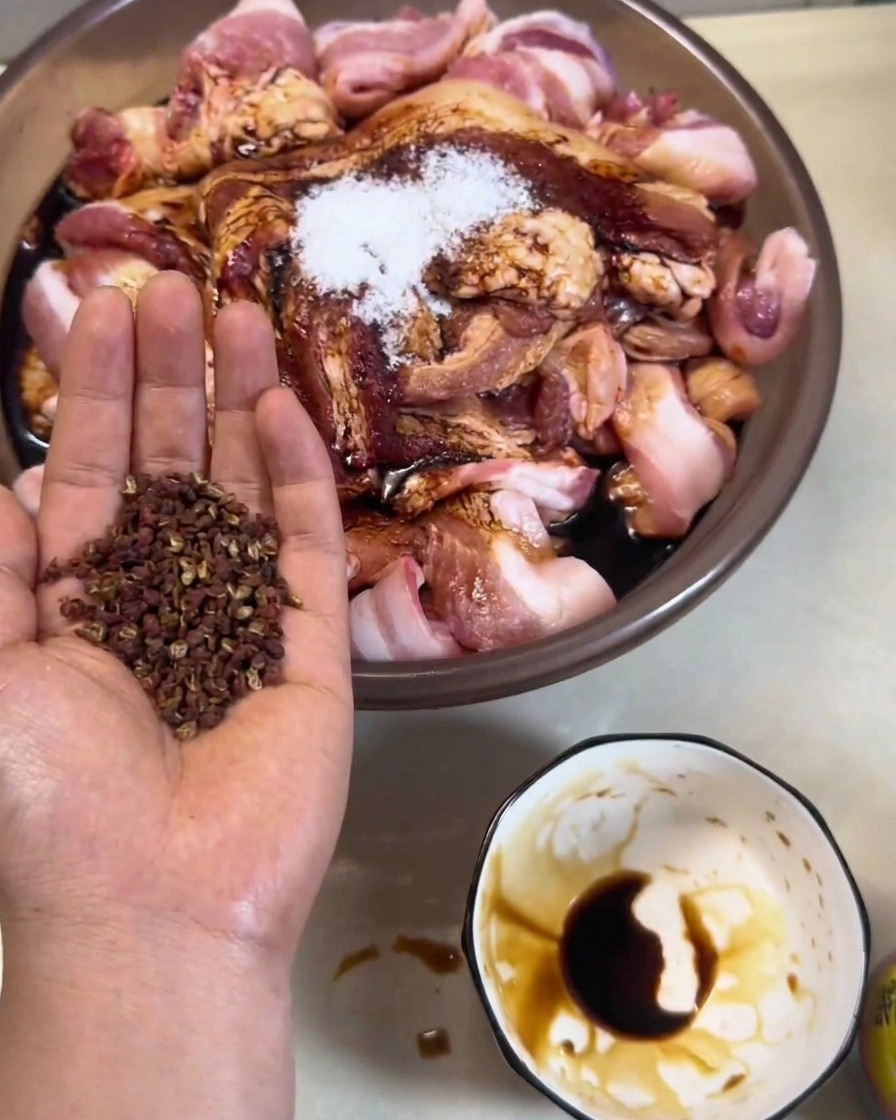 屋外のラックで、金属のフックに吊るされたマリネ済みの豚肉。