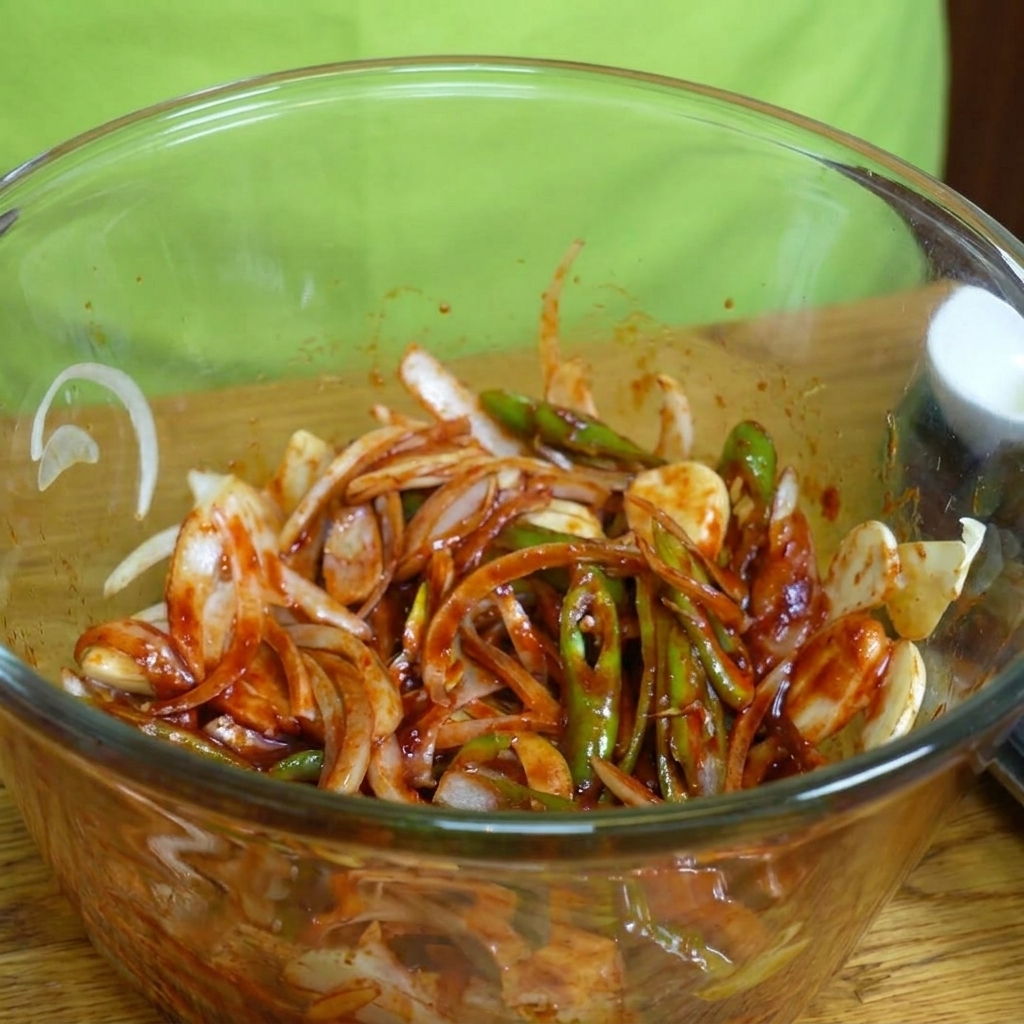 ボウルの中のタレと野菜に、豚バラ肉を加えている様子。