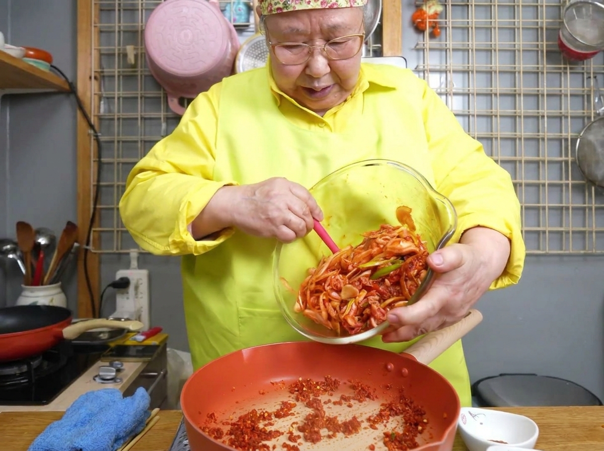 フライパンで豚肉と野菜が手際よく炒められている様子。